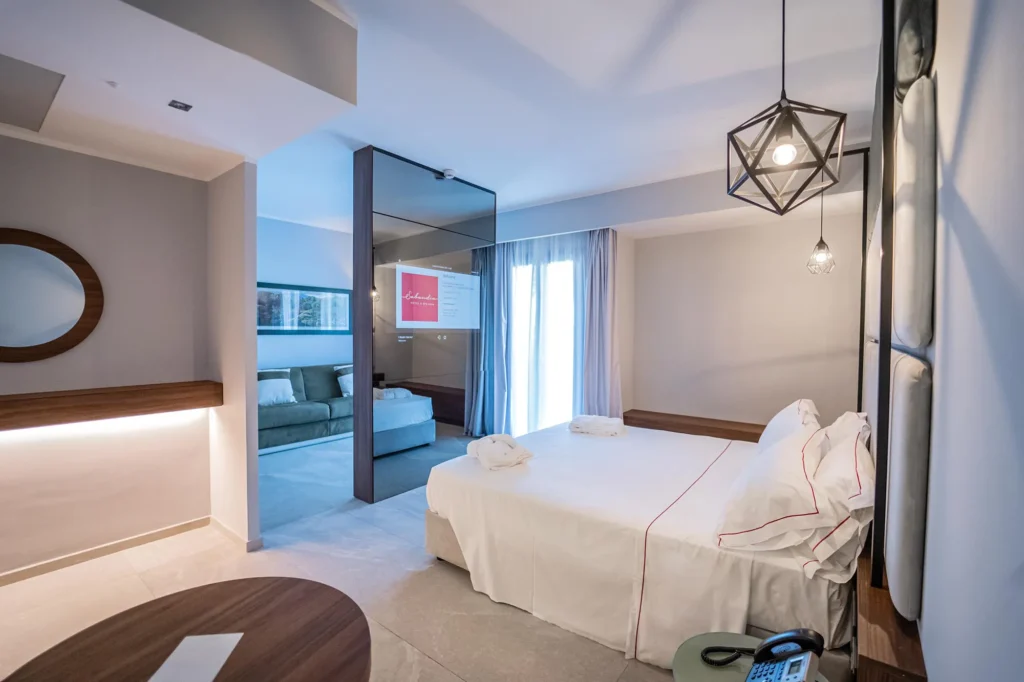 In the picture you see a small living room with a sofa and behind the wall the room with a double bed.