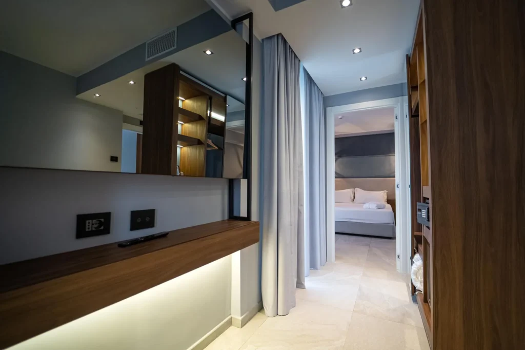 The picture shows the Suite's corridor leading to the bedroom. In the corridor a rectangular mirror and a wardrobe.